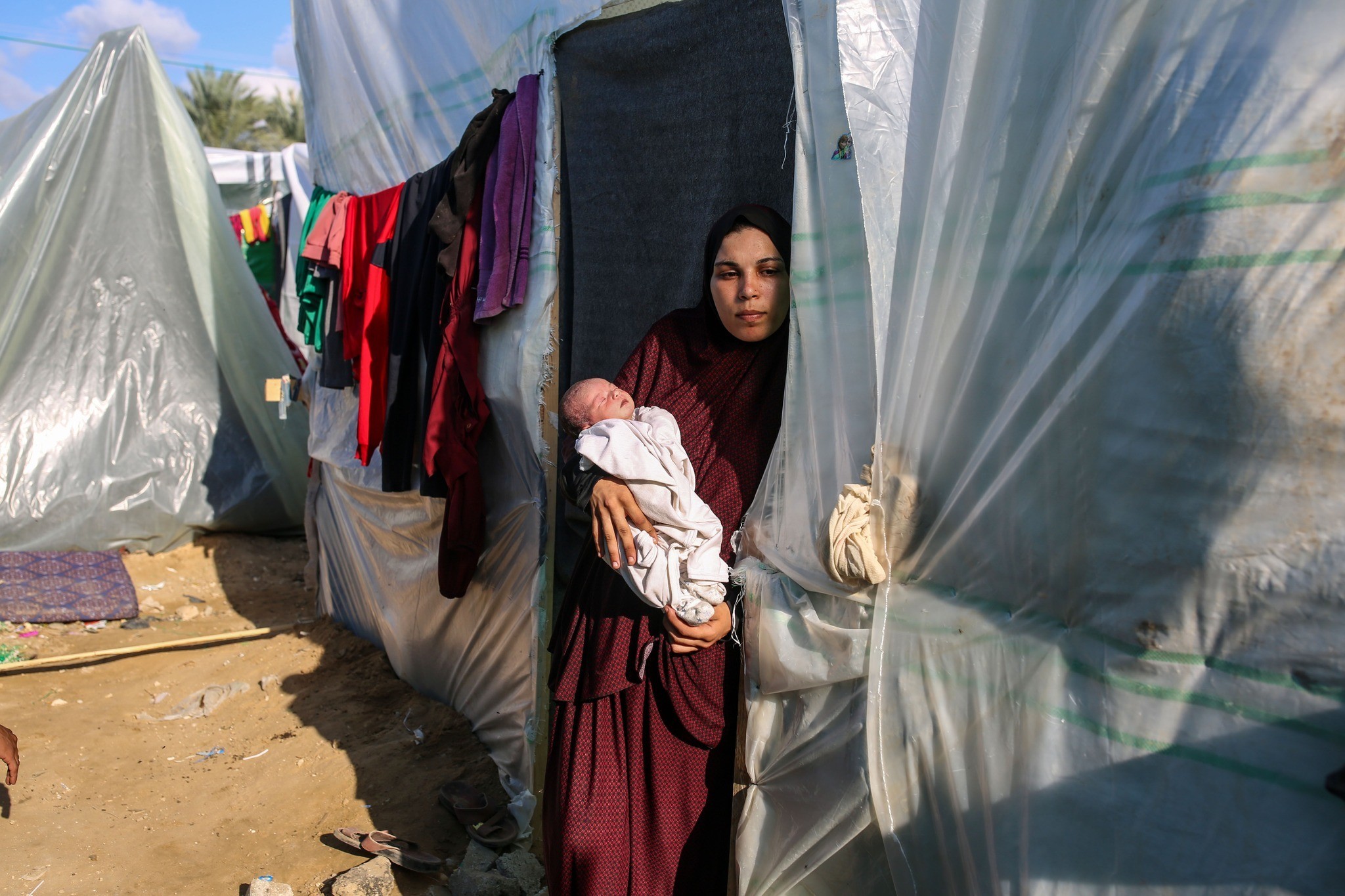 Frau mit Neugeborenem am Eingang zu einem Zelt in einem Flüchtlingslager im Gazastreifen, November 2023. Foto: Samar Abu Elouf