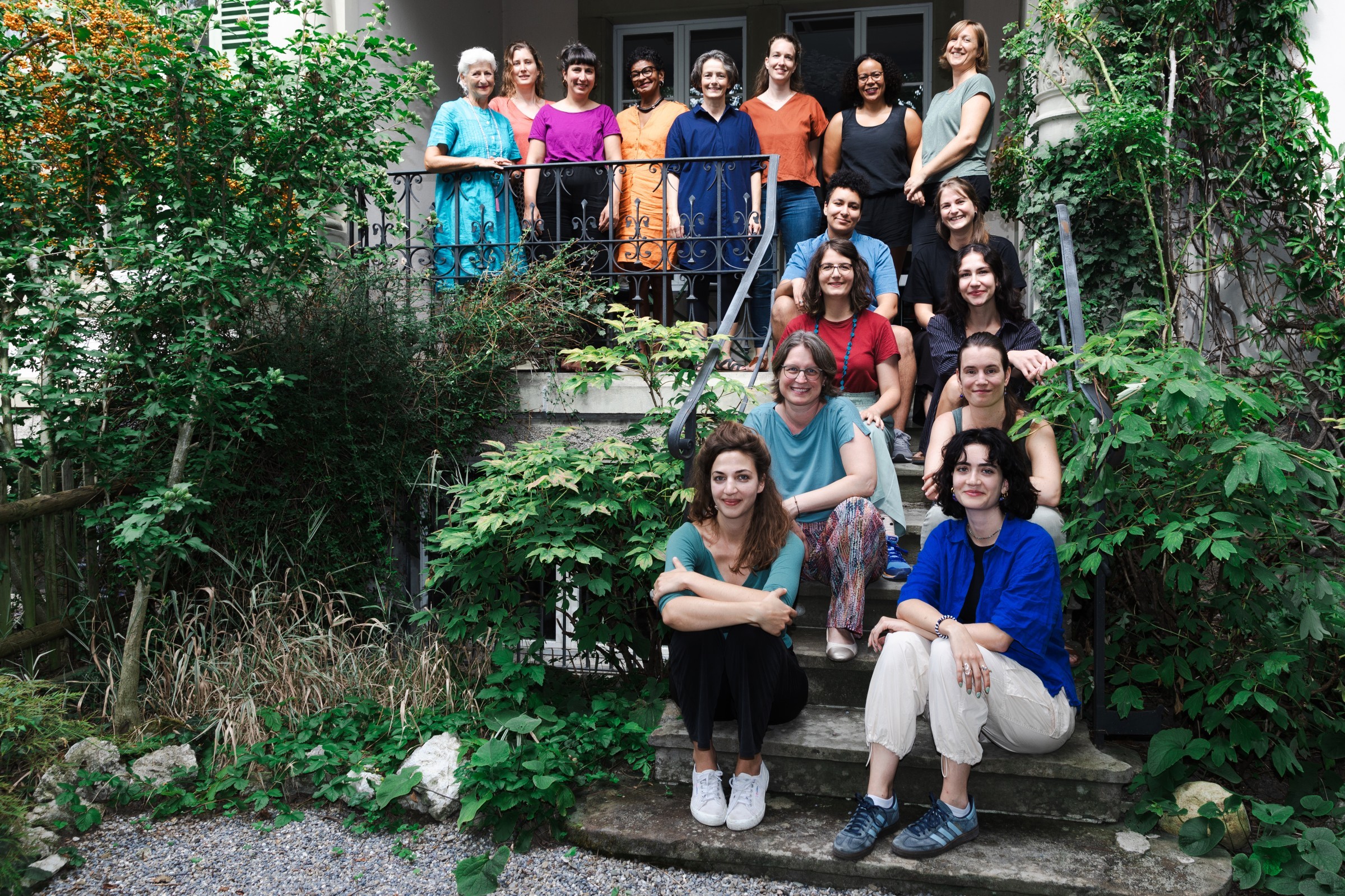 Das Frieda-Team: Frauen sitzen und stehen vor einem Haus.
