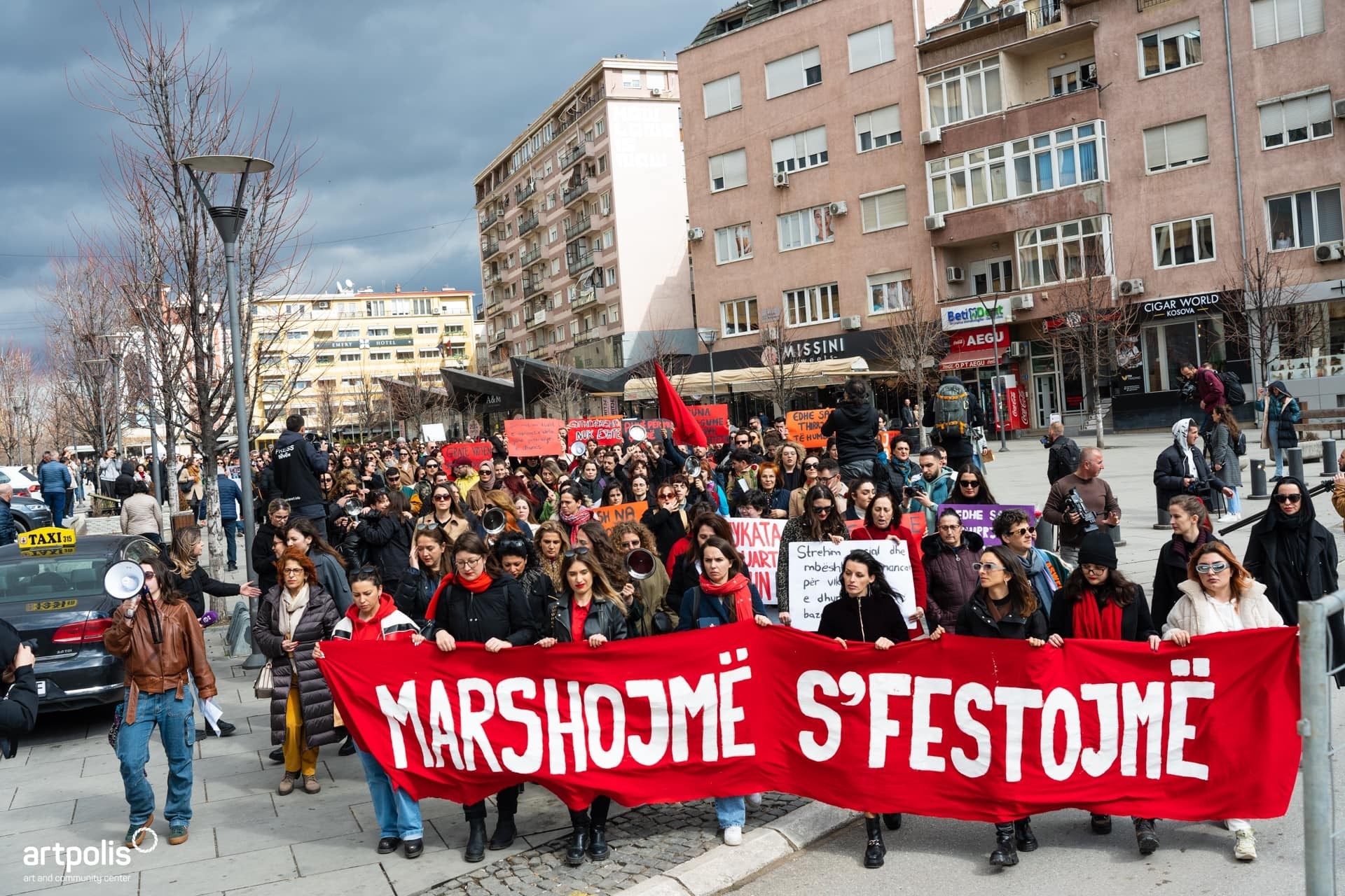 Frauenmasse demonstriert in Kosovo mit einem roten Banner.