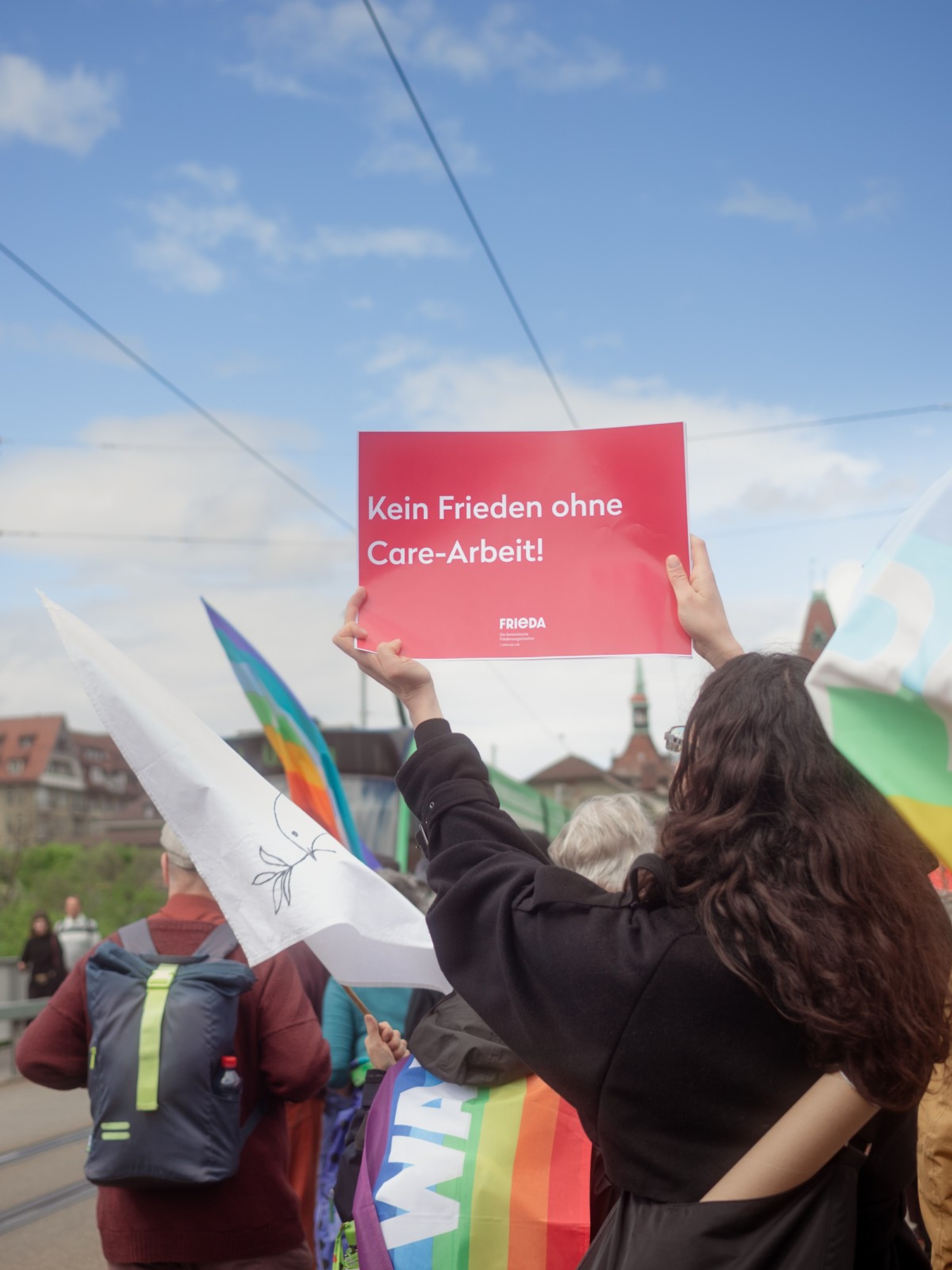 Frieda am Ostermarsch: Menschen marschieren mit Friedensflaggen und Schildern in Bern.