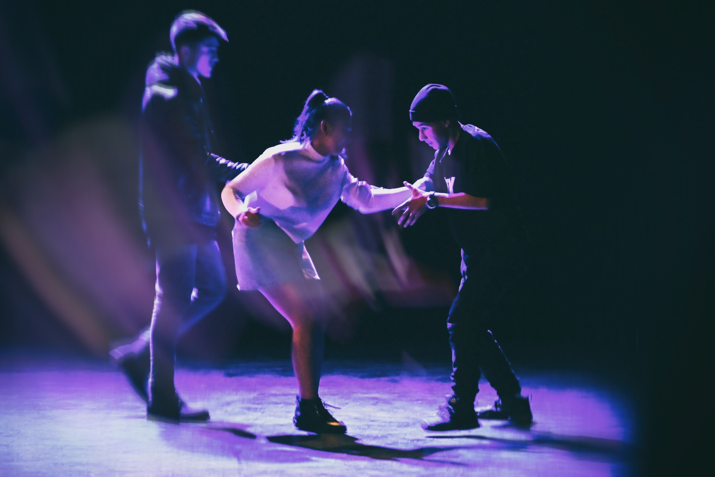 Ein Mädchen und zwei Jungen in Kosovo performen zusammen auf der Bühne für ein Theaterstück.
