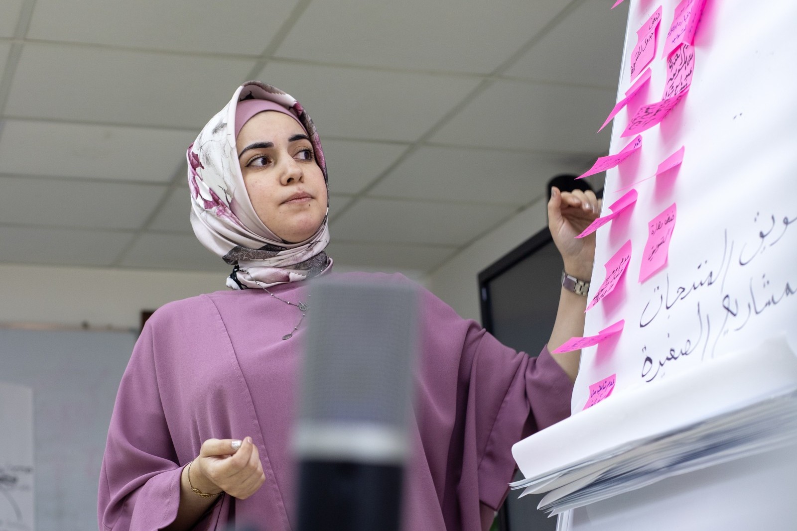 Junge Frau aus Palästina steht vor einem Flipchart Board.