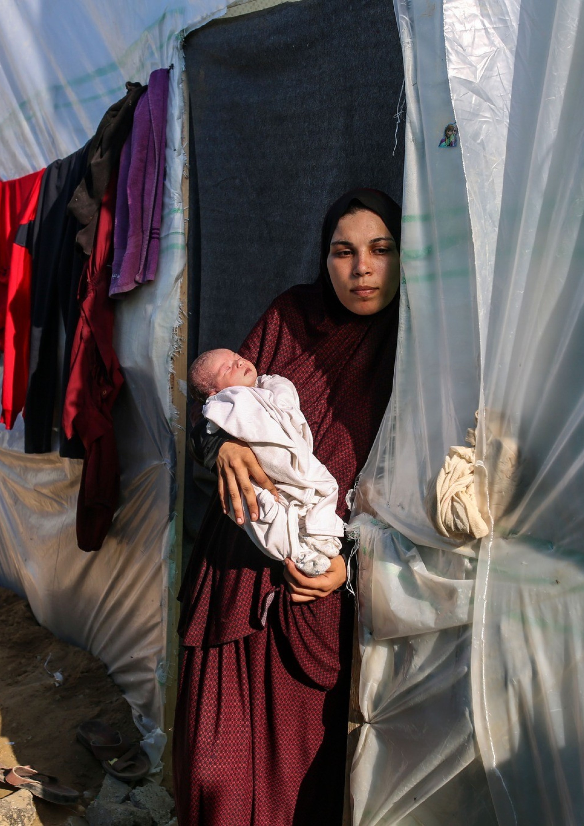 Frau mit Neugeborenem am Eingang zu einem Zelt in einem Flüchtlingslager im Gazastreifen, November 2023. Foto: Samar Abu Elouf