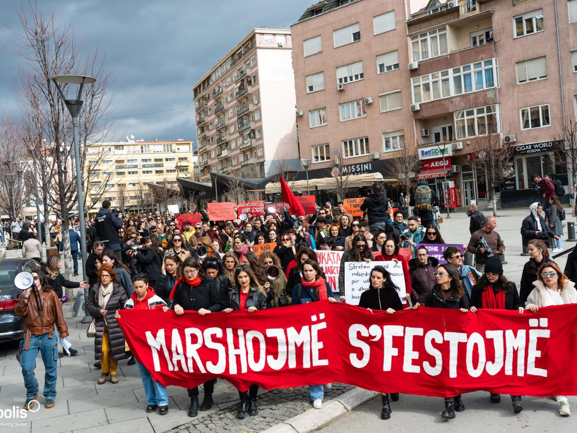 Frauenmasse demonstriert in Kosovo mit einem roten Banner.